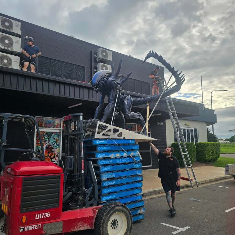 3D printed xenomorph sculpture being lifted by forklift during installation